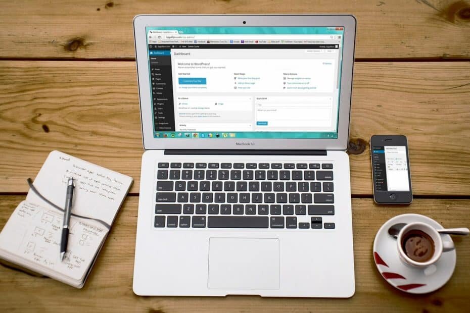Laptop, phone, notebook and coffee on a wooden desk